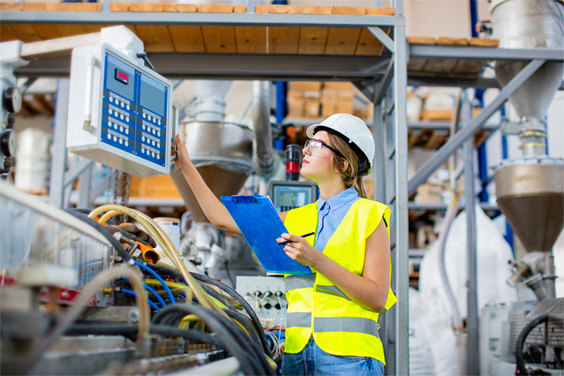 persona frente a unas máquinas anotando sobre una hoja.