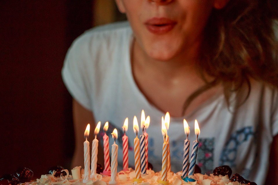 mujer soplando velas en un pastel