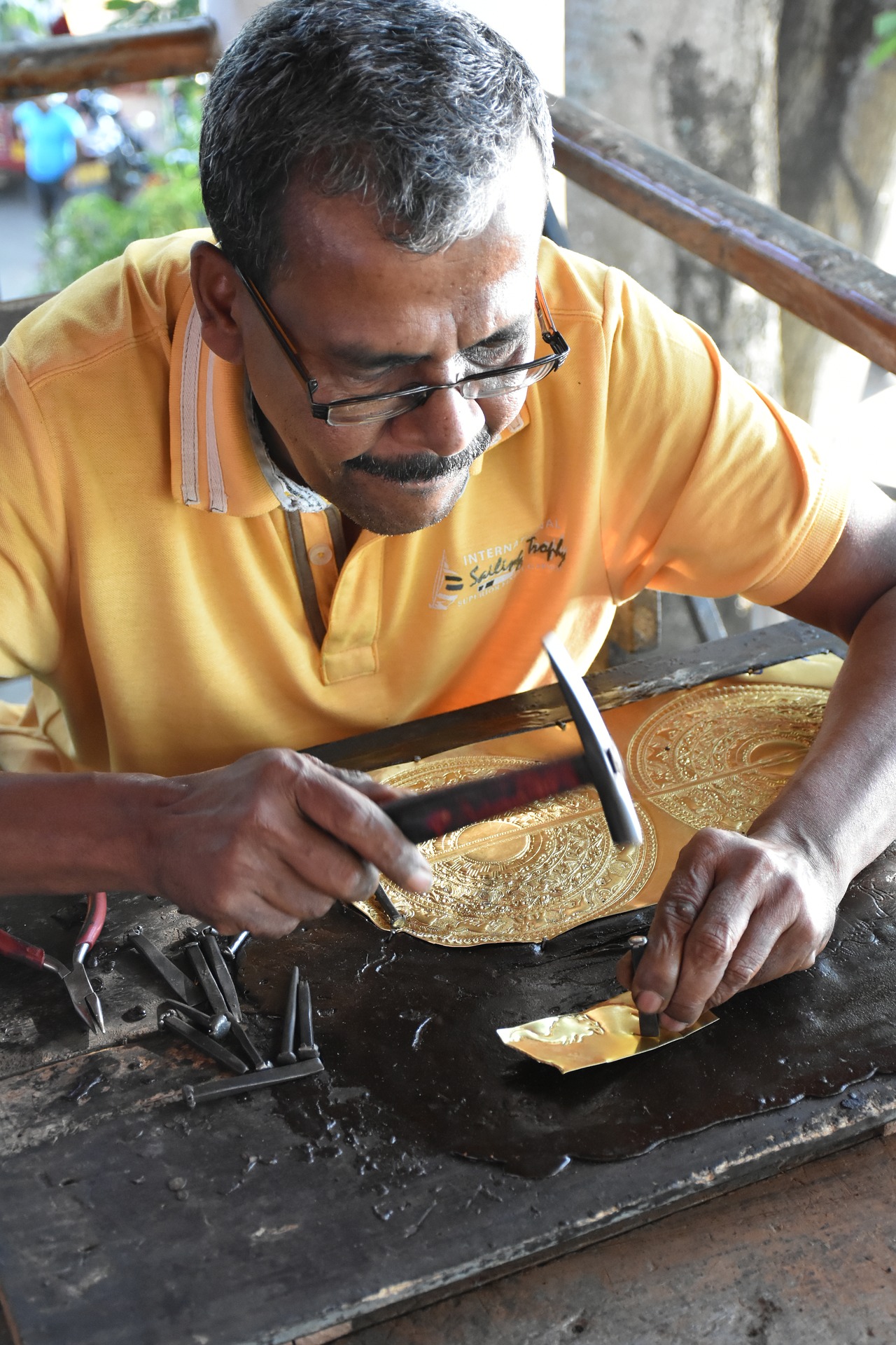 hombre con camiseta amarilla realiza artesanía.