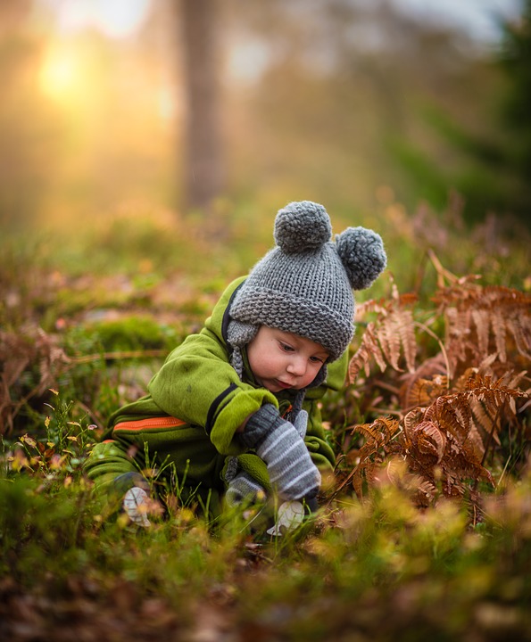 niño aproximadamente de 2 años sobre el pasto observando.