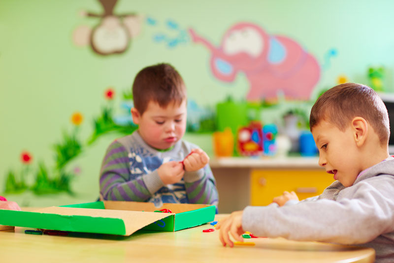 Niño con síndrome de Down en un salón de clases con otro niño sin discapacidad.