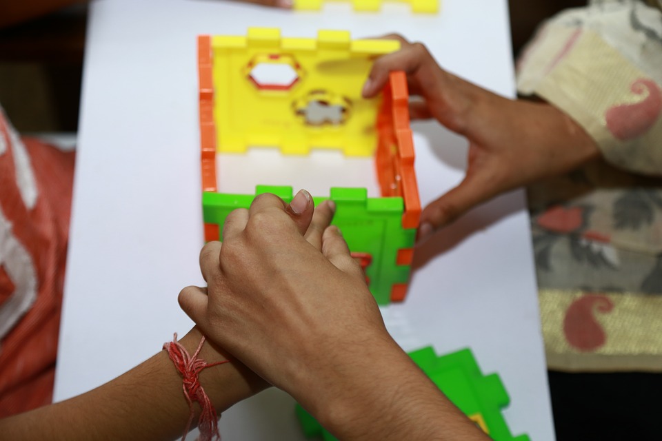 Manos de persona adulta dirigiendo las de un niño