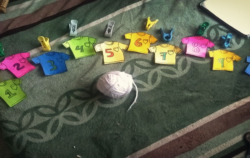Camisetitas de fomi numeradas del uno al diez, bola de estambre y ganchos de ropa.