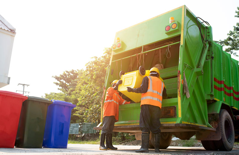 Trabajadores de limpia vacían el contenido de un bote de basura al camión de recolección.
